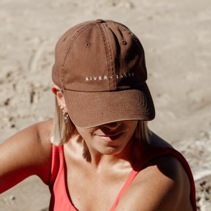 Girl on the beach wearing the brown southern dad cap.