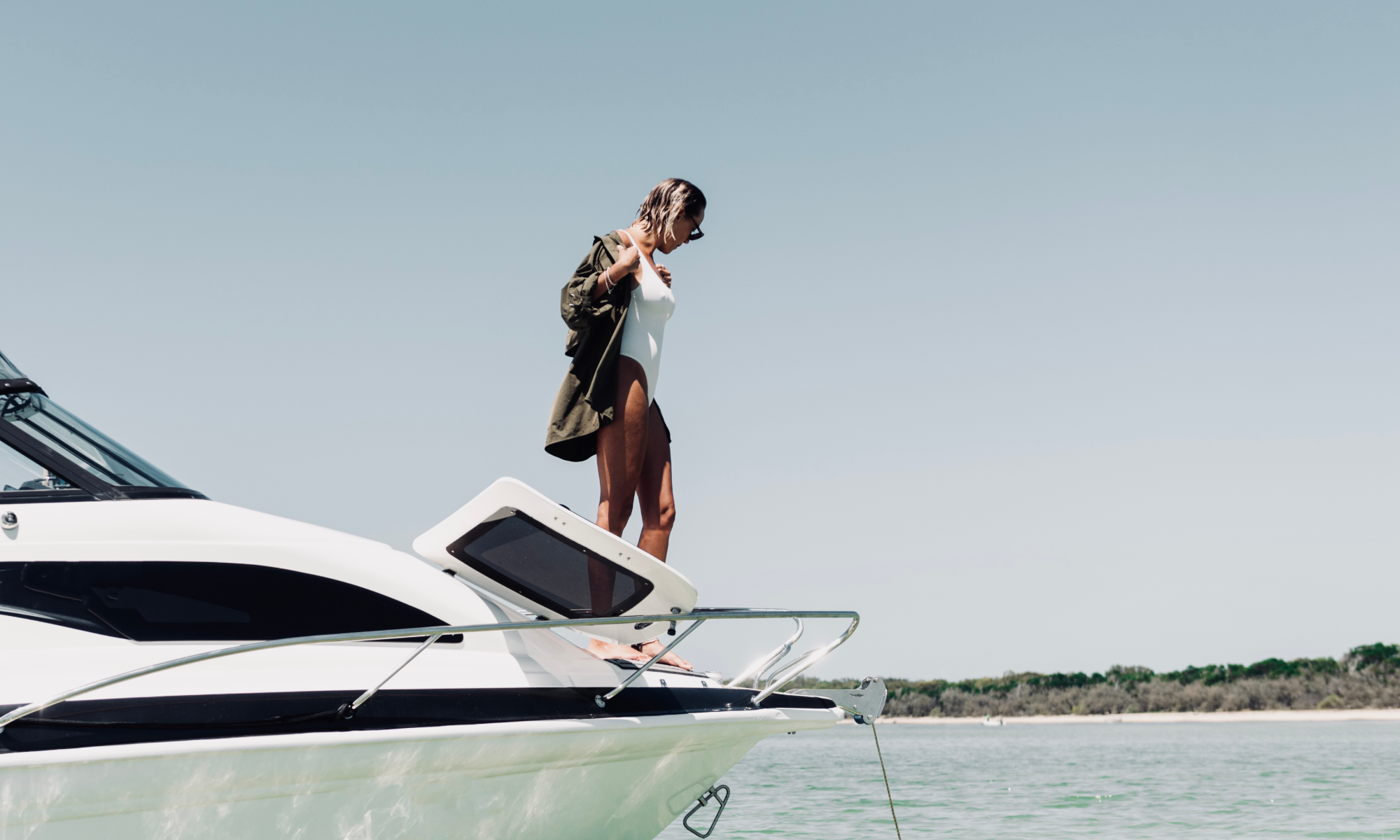 Woman standing on a boat with clear blue sky and water in the background