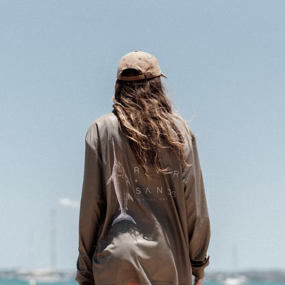 Back of a woman wearing the sands fishing shirt by the ocean.