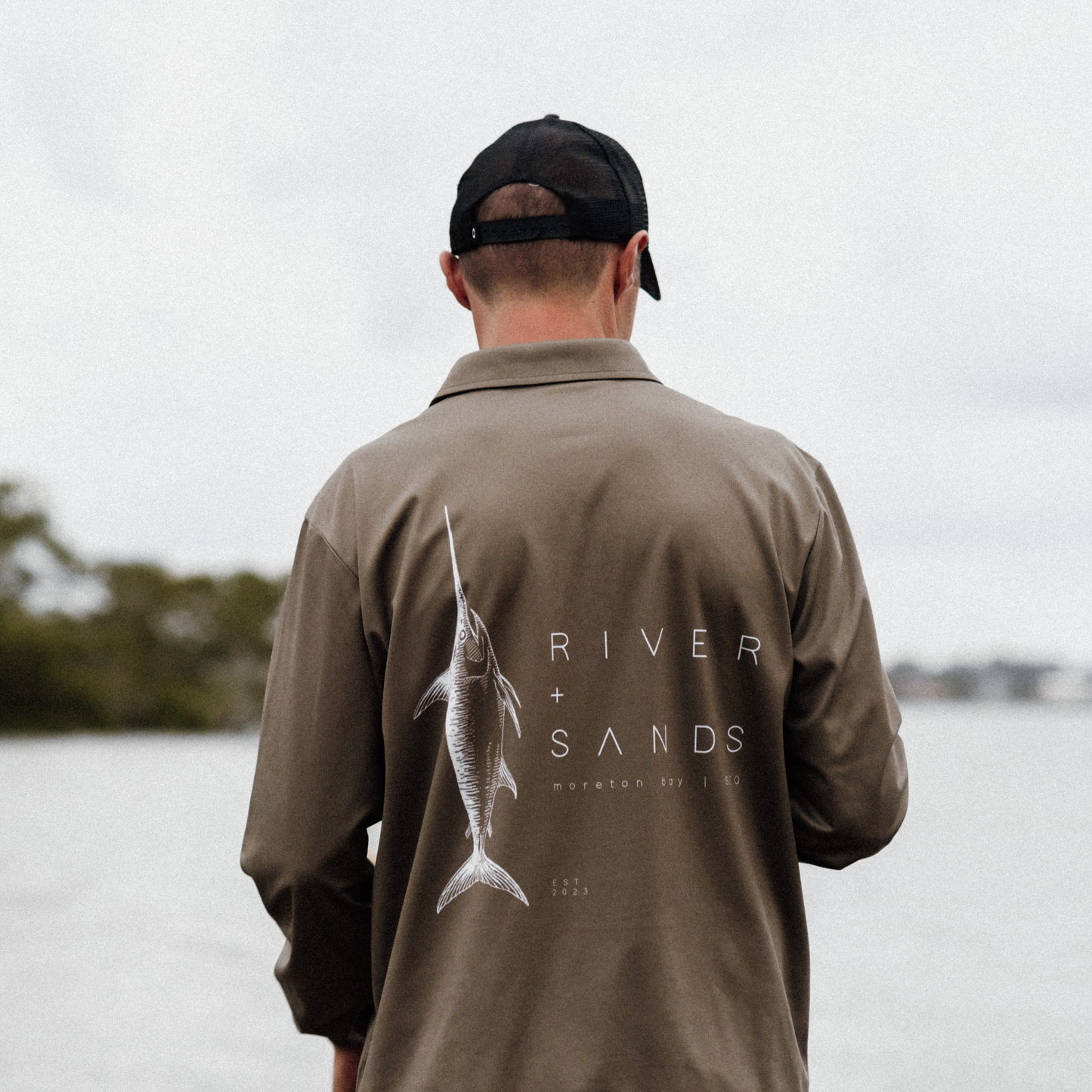 Back of a man wearing the khaki sands fishing shirt on the river bank.