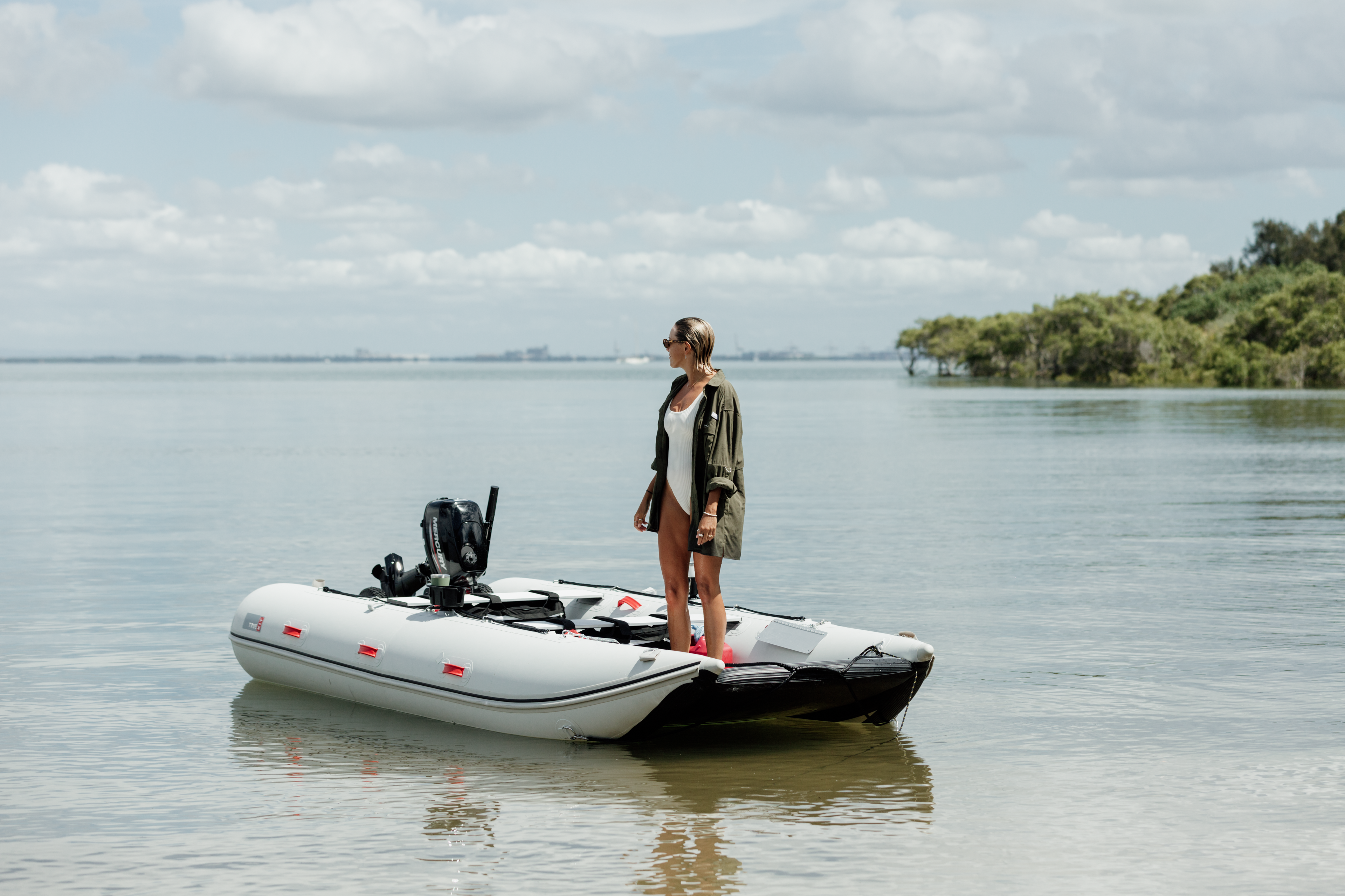 Woman standing on an inflatable boat wearing a long sleeve UPF50+ River and Sands adventure shirt in Moreton Bay, Brisbane.
