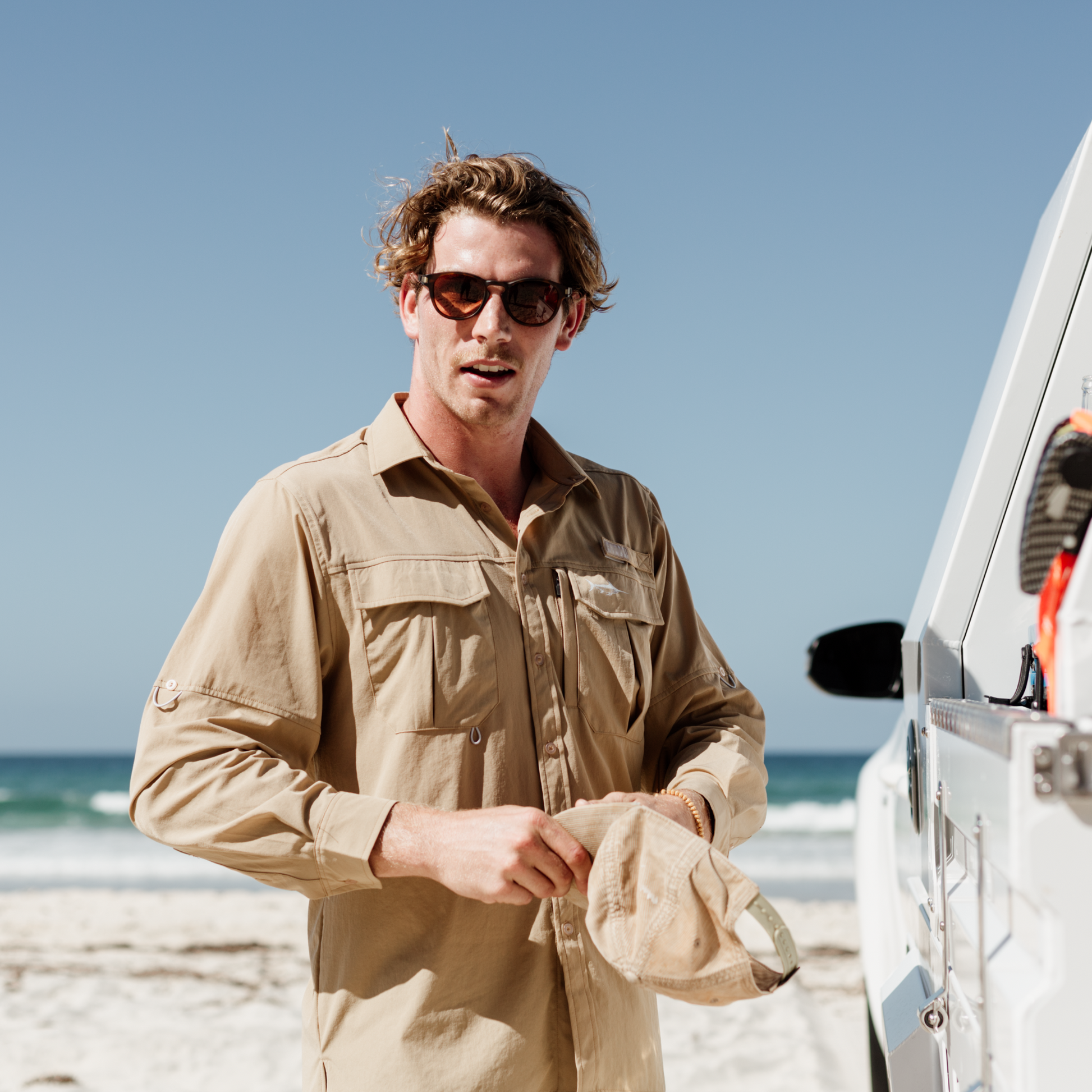 Man wearing the tan river adventure shirt on the beach.