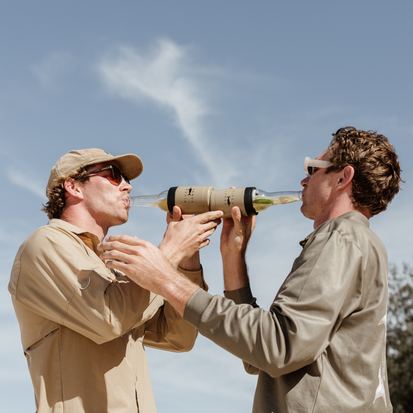 Two boys drinking from the tan river and sands can cooler.