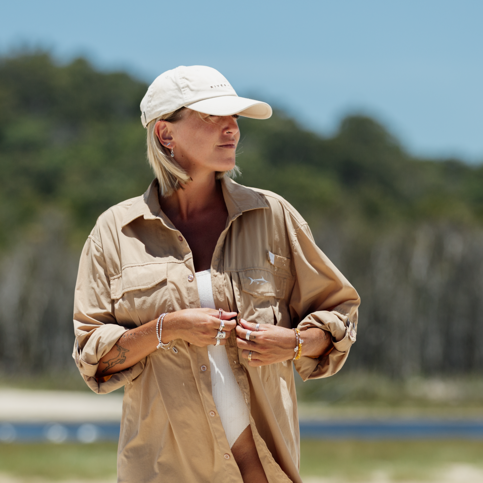 Woman on Stradbroke Island wearing a river and sands tan adventure shirt and beige dad cap.