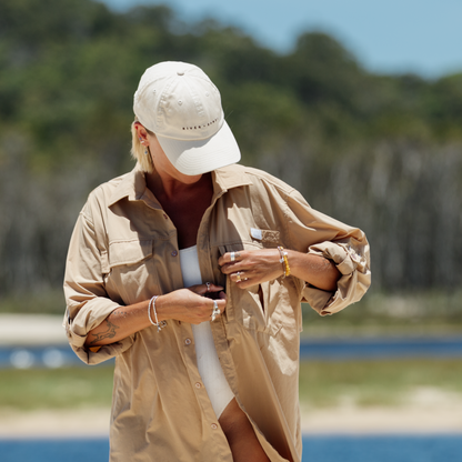 Woman on Stradbroke Island wearing a river and sands tan adventure shirt and beige dad cap.