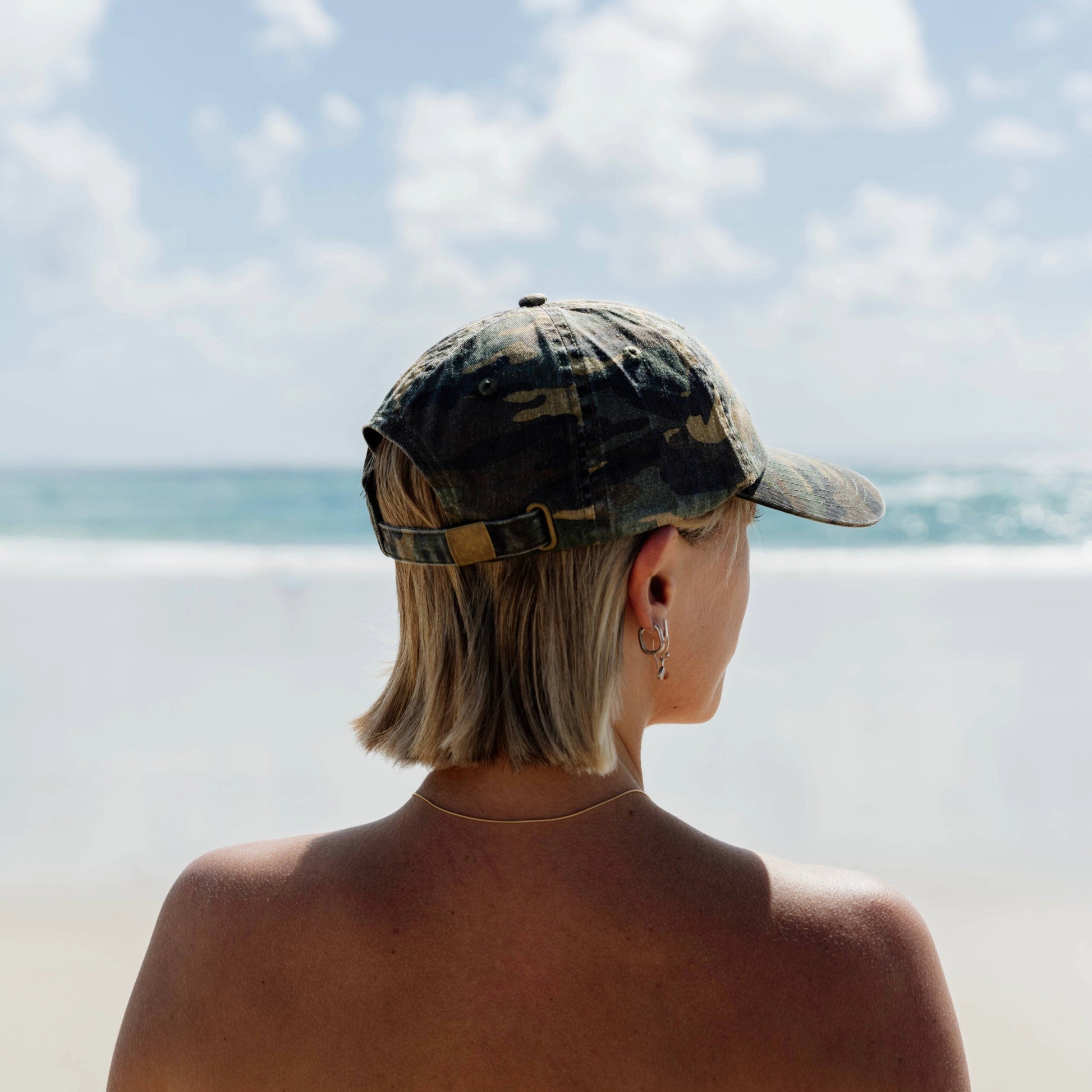 Person wearing a camouflage cap looking at the ocean
