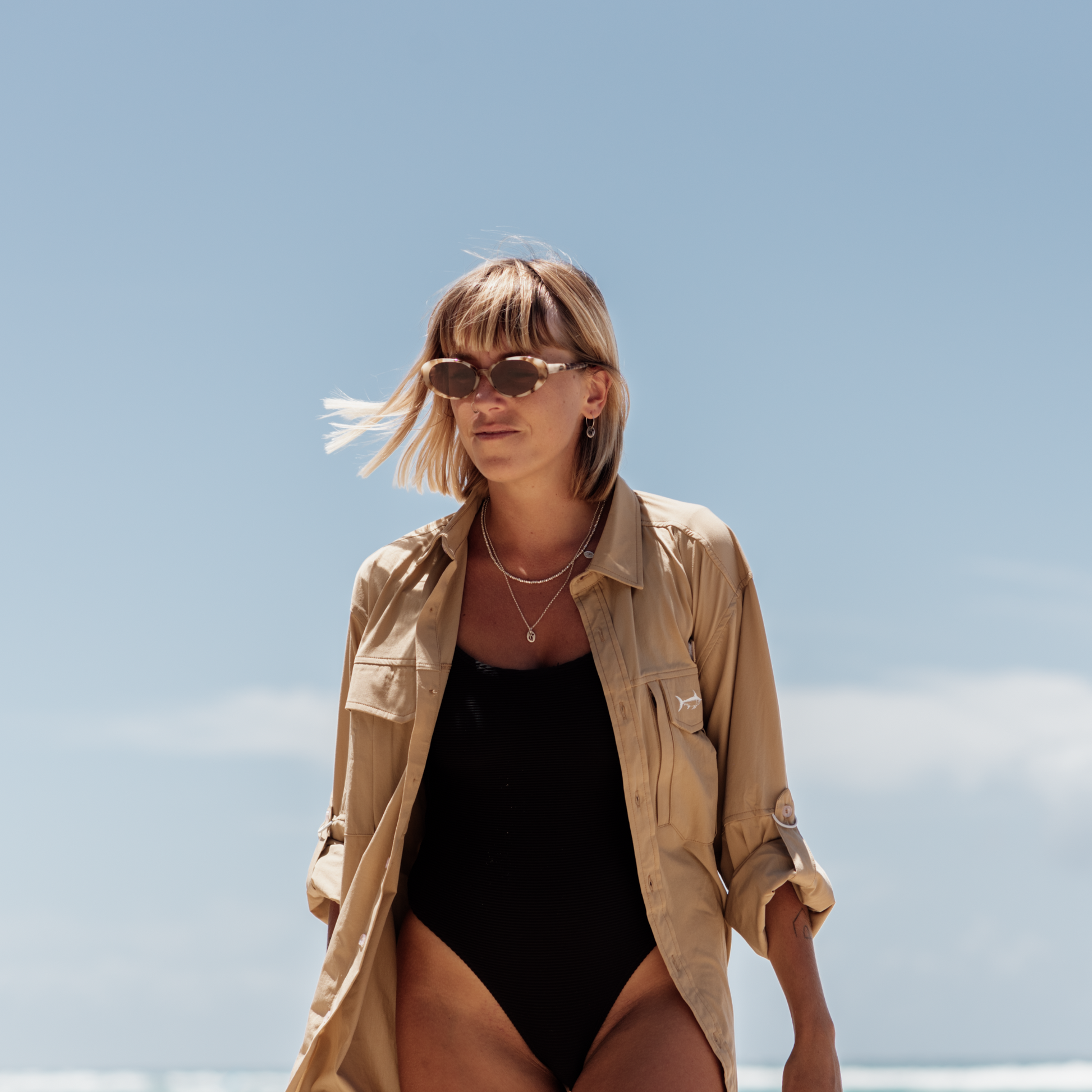 Woman at the beach wearing the tan river adventure shirt over her bathers.